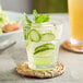 An Acopa Endure Tritan plastic rocks glass of water with cucumber slices and mint leaves.
