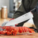 A person using a Schraf chef knife to cut a lobster.