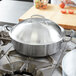 A Vollrath stainless steel high domed cover on a pot.