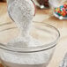 A spoon pouring ADM All Purpose Flour into a bowl.