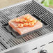 A square Himalayan salt slab with shrimp on a grill.