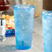Two blue Choice plastic tumblers filled with ice on a table.