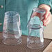 A woman holding a pair of Choice clear plastic tumblers.