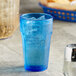 A blue Choice plastic tumbler with ice and a straw on a table.