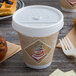 A Dart white plastic sip thru lid on a coffee cup with a waffle and pastries on a table.