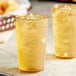 Two Choice amber plastic tumblers filled with ice tea on a table.