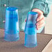 A woman holding a pair of blue Choice plastic tumblers.