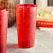 A close-up of a red Choice plastic tumbler with ice and a straw.