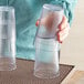 A person holding a stack of clear plastic Choice tumblers.