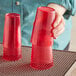 A person holding a stack of red plastic cups.