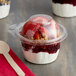 A Dart SafeSeal plastic deli container filled with yogurt, strawberries, and granola with a dome lid.