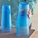 A woman holding a stack of blue Choice plastic tumblers.