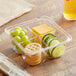A Dart plastic container with crackers, grapes, and cheese.