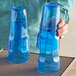 A person holding a pair of Choice blue plastic cups.