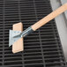 A wood block with a metal handle and bristles on a Thunder Group grill cleaning brush.