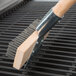 A Thunder Group single head grill brush with a wooden handle.