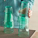 A person holding a pair of green Choice plastic tumblers.