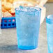 A blue plastic Choice pebbled tumbler with ice water on a table.