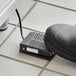 A black cushioned foot pedal with a black cord.