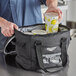 A man using a Vollrath small insulated cooler bag to hold six large beverages.