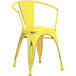 A Lancaster Table & Seating yellow metal outdoor arm chair with black legs.