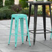 Two Lancaster Table & Seating distressed seafoam barstools on an outdoor patio.