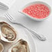 A plate of oysters with a fork and a bowl of pink sauce.
