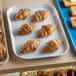 A white Cambro market tray of pastries on a bakery display counter.
