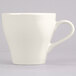 A close-up of a Tuxton Europa eggshell white coffee cup with a white handle.