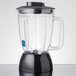 A Waring blender jar with a clear lid and a black handle.