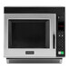 An Amana stainless steel commercial microwave with a black door.