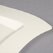 A white Fineline plastic square plate with a wavy edge.