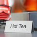 A double sided stainless steel table tent sign that says "Hot Tea" on a table.