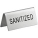 A silver stainless steel table tent sign with black text that reads "Sanitized" 