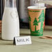 A double sided stainless steel table tent labeled "Milk" on a table.
