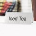 A stainless steel table tent sign that says "Iced Tea" on a table with a cup of tea.