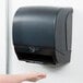 A person using a black Response DISP 235 hands-free paper towel dispenser.