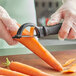 A person using the Choice 6" Smooth Vegetable Peeler to peel a carrot.