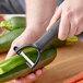 A person using a Choice 6" Julienne "Y" Peeler to julienne a zucchini.
