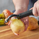 A person using a Choice serrated vegetable peeler to peel a potato.