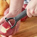 A person using a Choice serrated "Y" peeler to peel a potato.