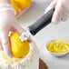 A hand using the Choice Citrus Zester to peel a lemon.