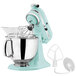 A white KitchenAid tilt-head countertop mixer with a silver bowl and mixer attachment in aqua.