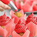 A close-up of a cupcake with bright red frosting.