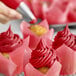 A close-up of a cupcake with pink frosting made using Chefmaster Super Red food coloring.