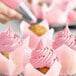 A cupcake with pink frosting made using Chefmaster Rose Pink food coloring.