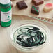 A bowl of white liquid with green and black swirls using Chefmaster Green Oil-Based Candy Color.
