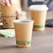 A hand holding a brown EcoChoice paper hot cup with a white lid.