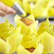 A close-up of a yellow swirl of Chefmaster Lemon Yellow food coloring on cupcakes.