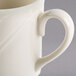 A close-up of a Homer Laughlin ivory china mug with a curved handle.